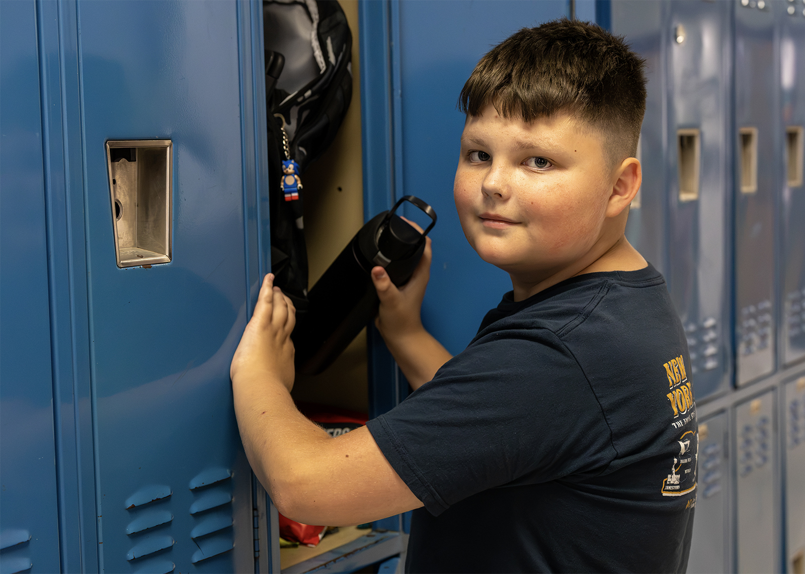 middle school student at locker getting water bottle