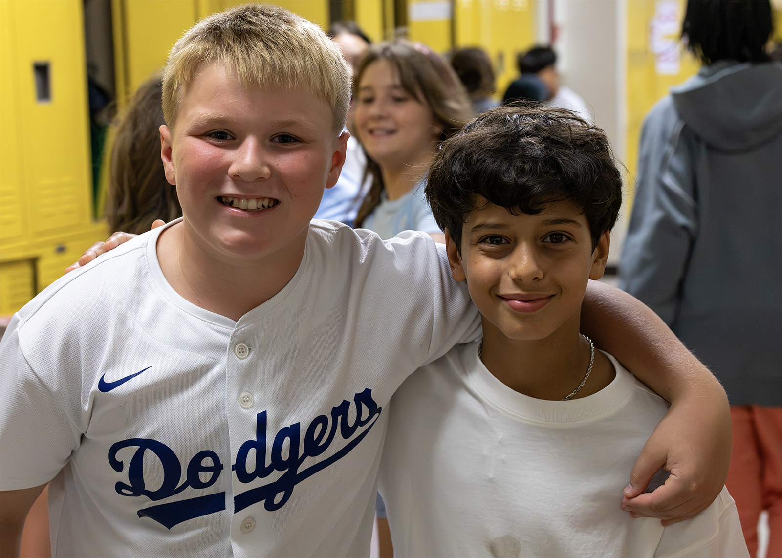 two middle school students smile in busy hallway