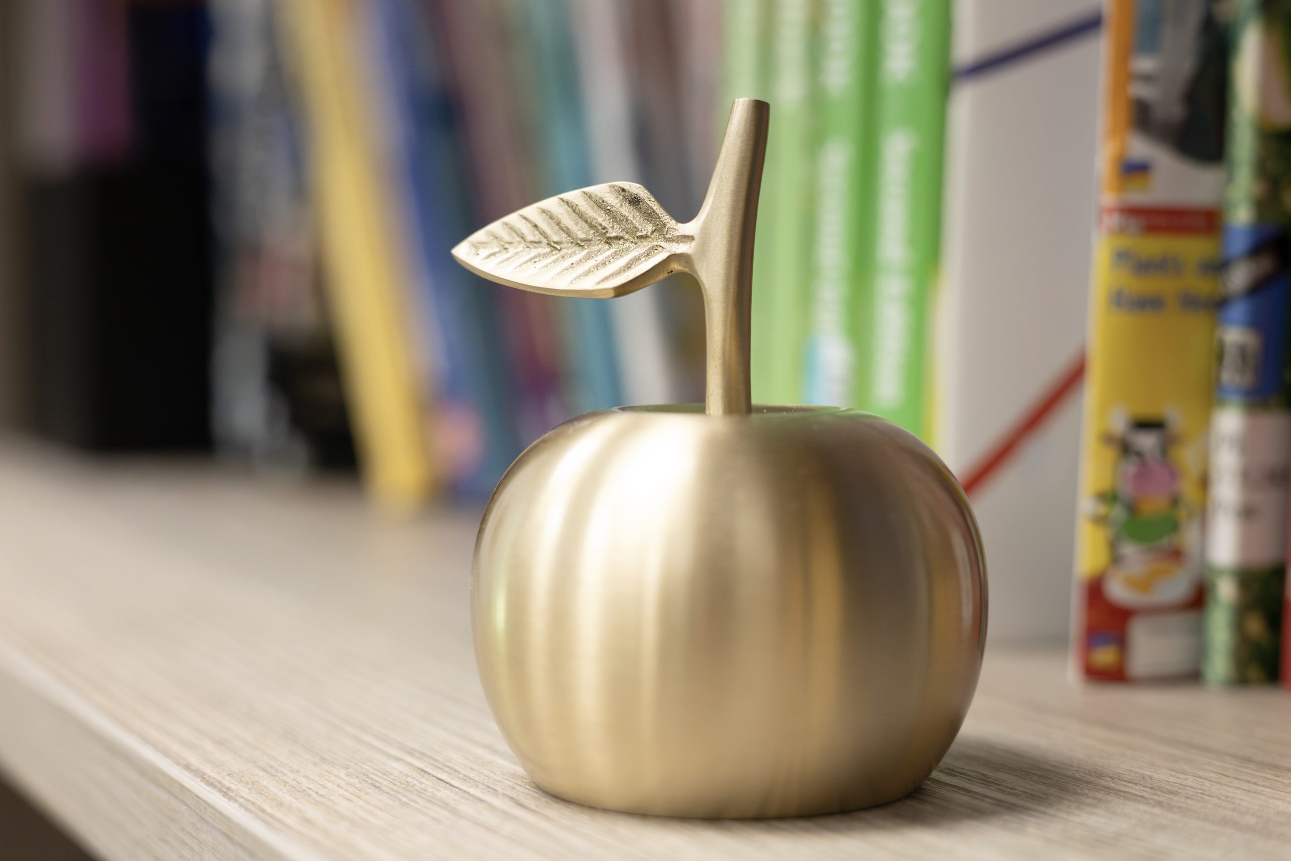 Gold apple on bookshelf.