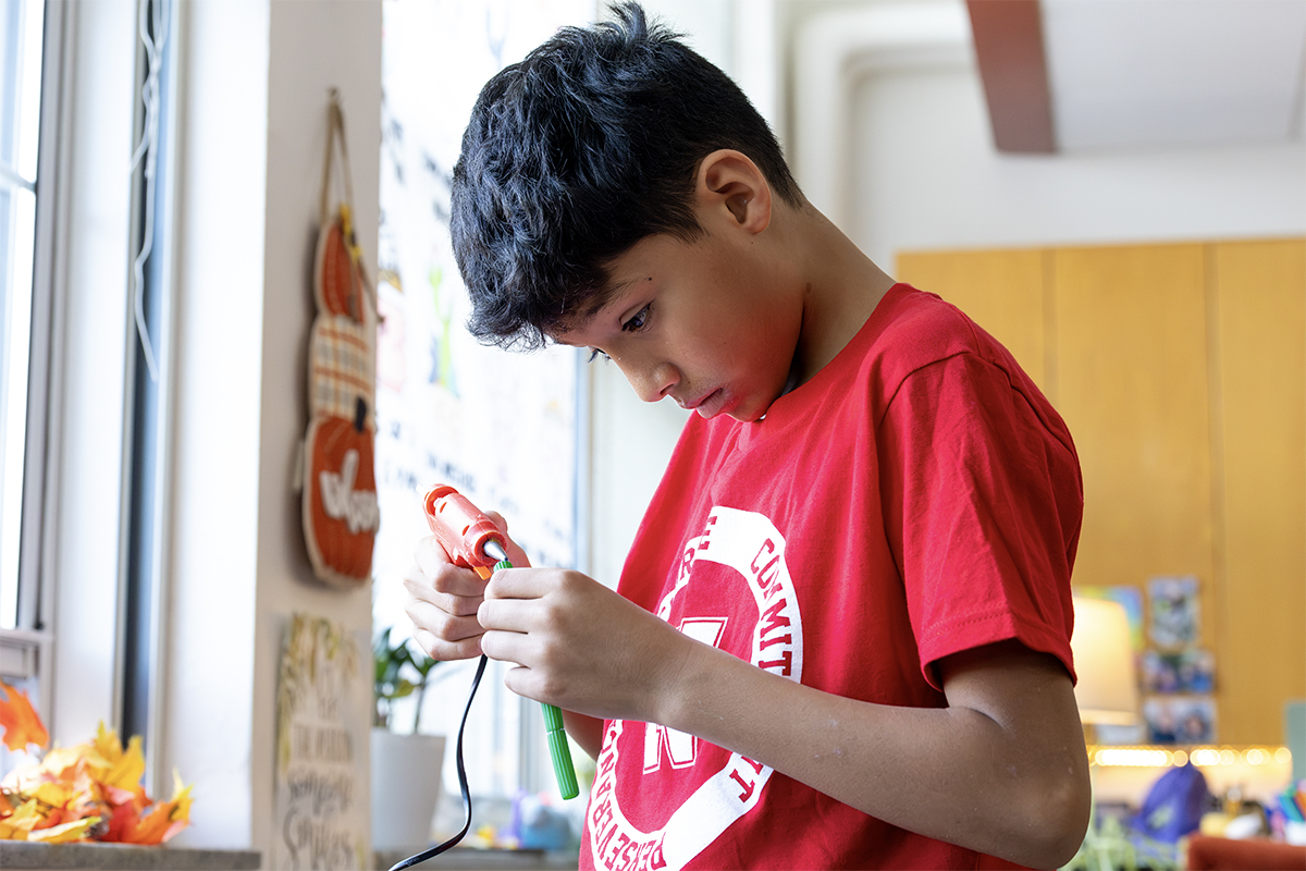middle school student hot gluing a project 