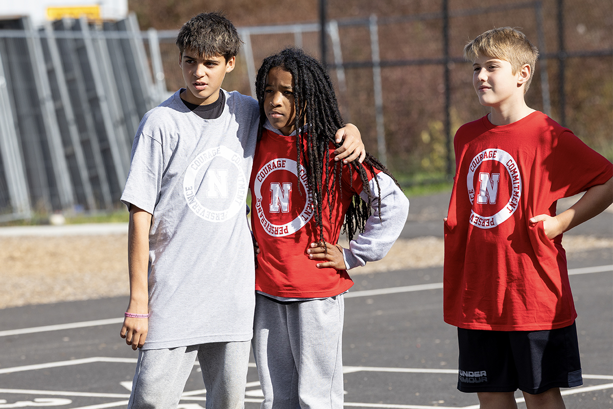 middle school students with arms around each other on playground 